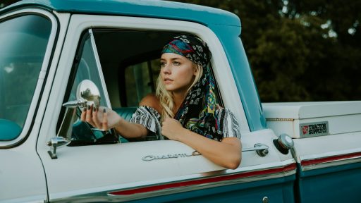 photography of woman holding side mirror in white and green 2-door pickup truck