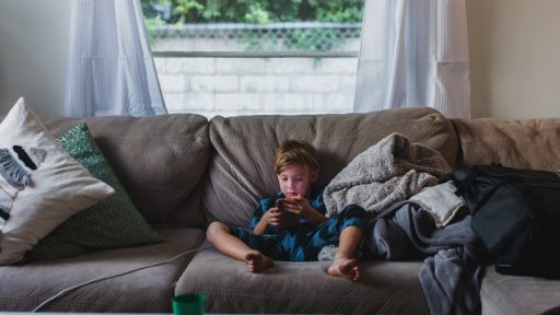 boy in blue shirt lying on gray couch