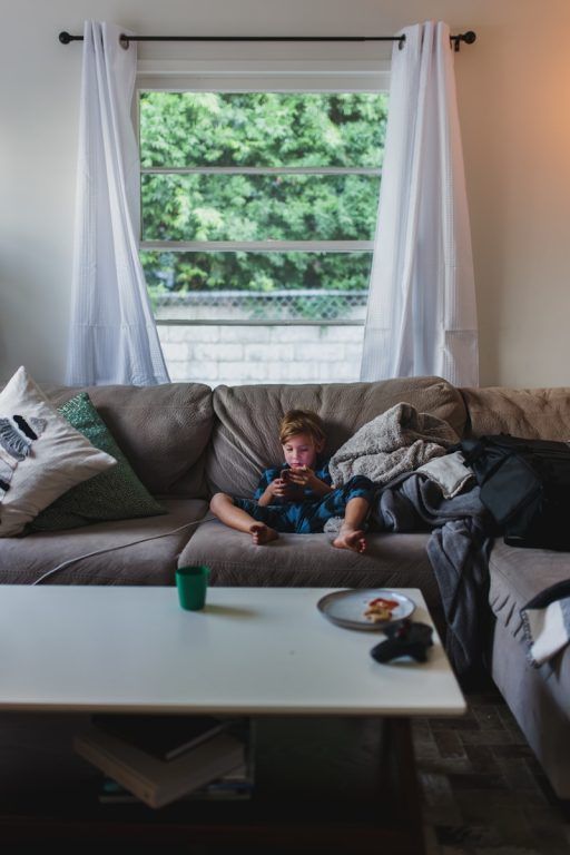 boy in blue shirt lying on gray couch