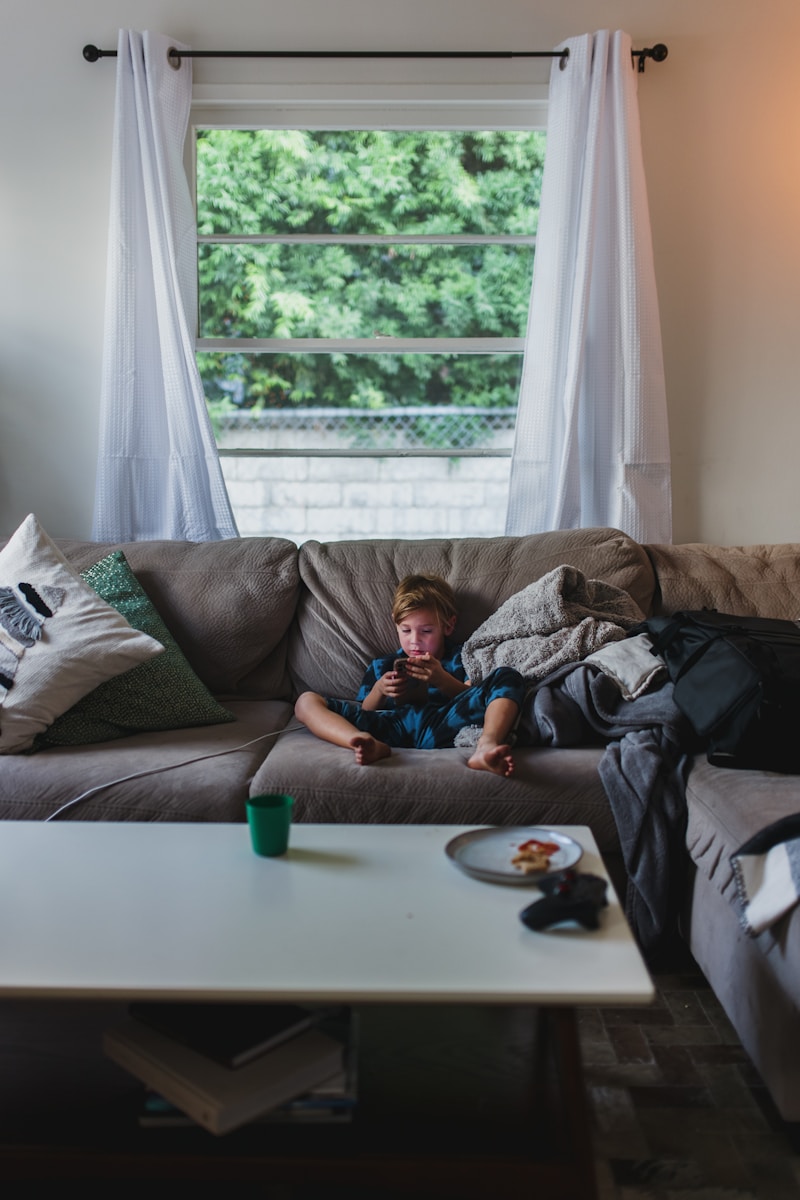 boy in blue shirt lying on gray couch