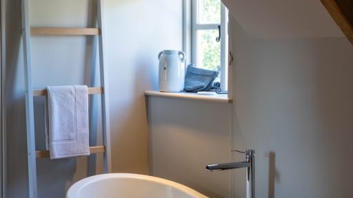 wooden ladder rack near white and black ceramic bathtub