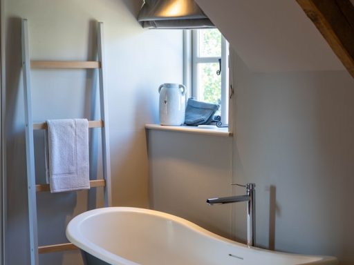 wooden ladder rack near white and black ceramic bathtub