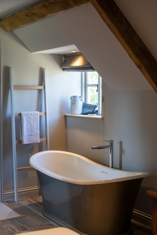 wooden ladder rack near white and black ceramic bathtub