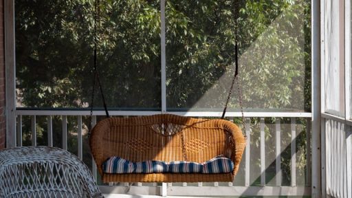 a deck with a hammock and a chair and a window with trees in the background