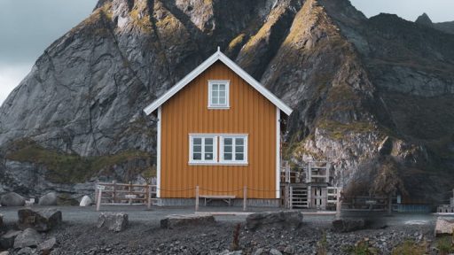 Charming yellow house nestled by rugged mountains in Nordland, Norway.