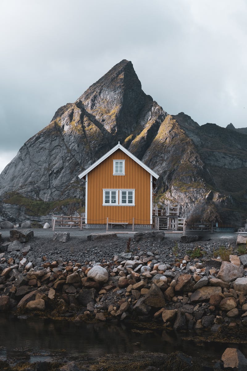 Charming yellow house nestled by rugged mountains in Nordland, Norway.