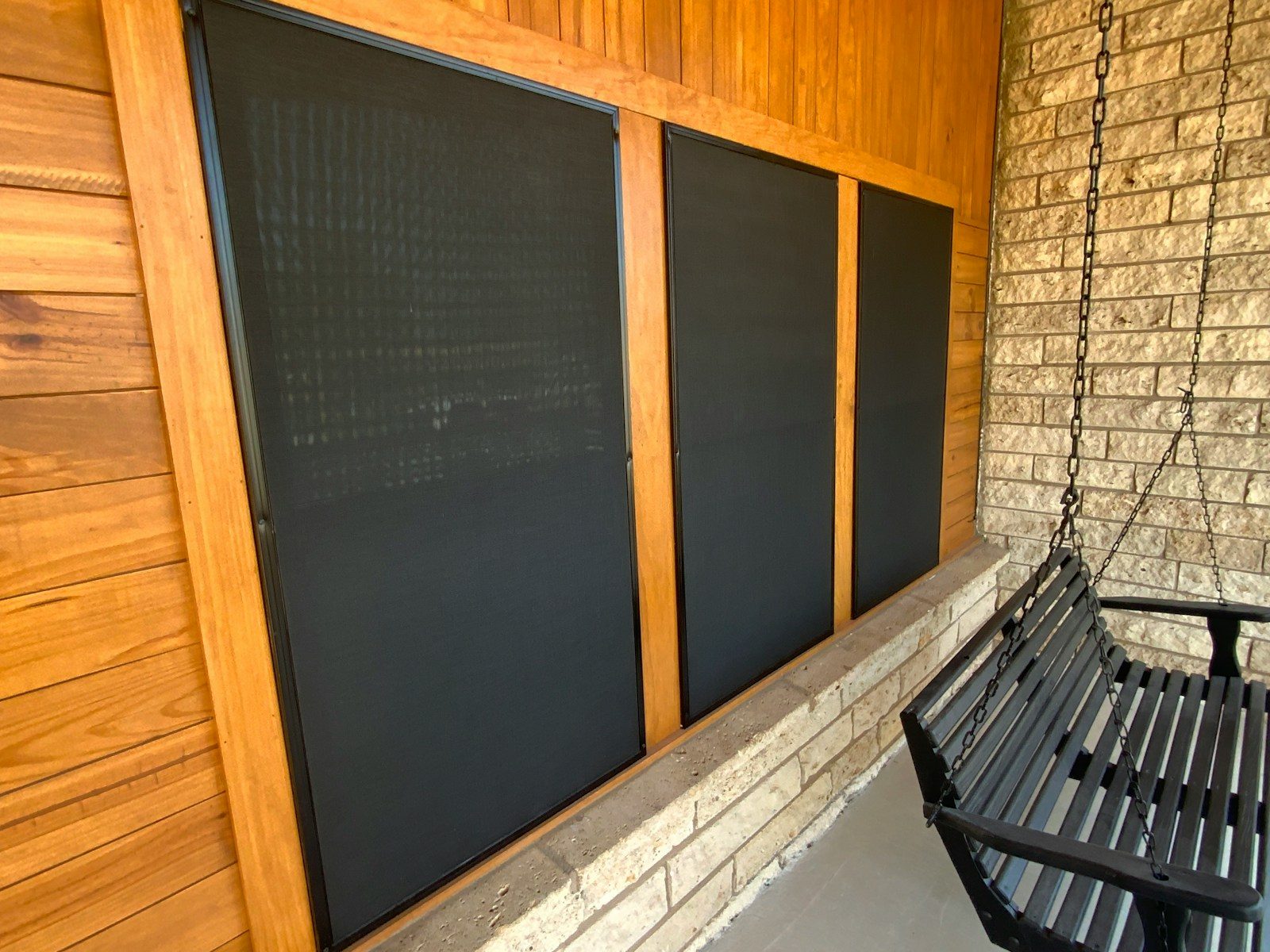A black bench sitting next to a brick wall