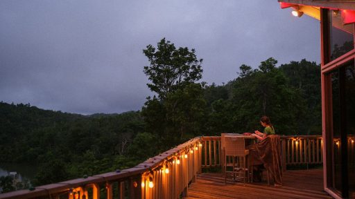 a woman sitting at a table on top of a wooden deck