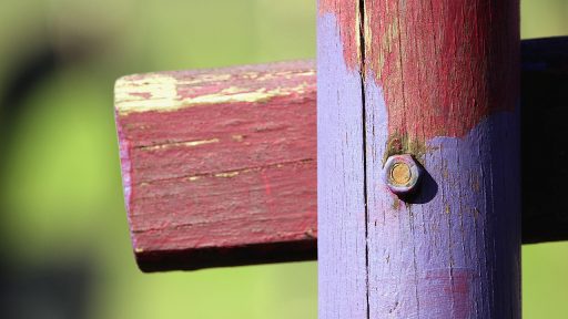 Persoon die een houten schutting schildert met een kwast in de tuin