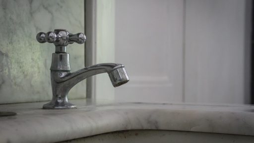 Authentieke jaren-30-badkamer met roomwitte metrotegels en klassiek sanitair op voetstuk