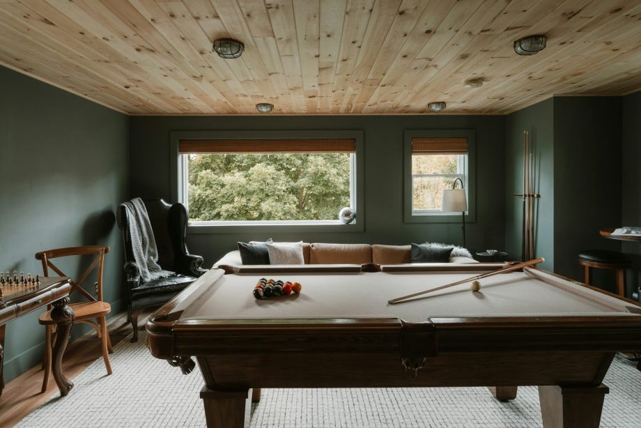 Pool table in a room with wood ceiling and sofa